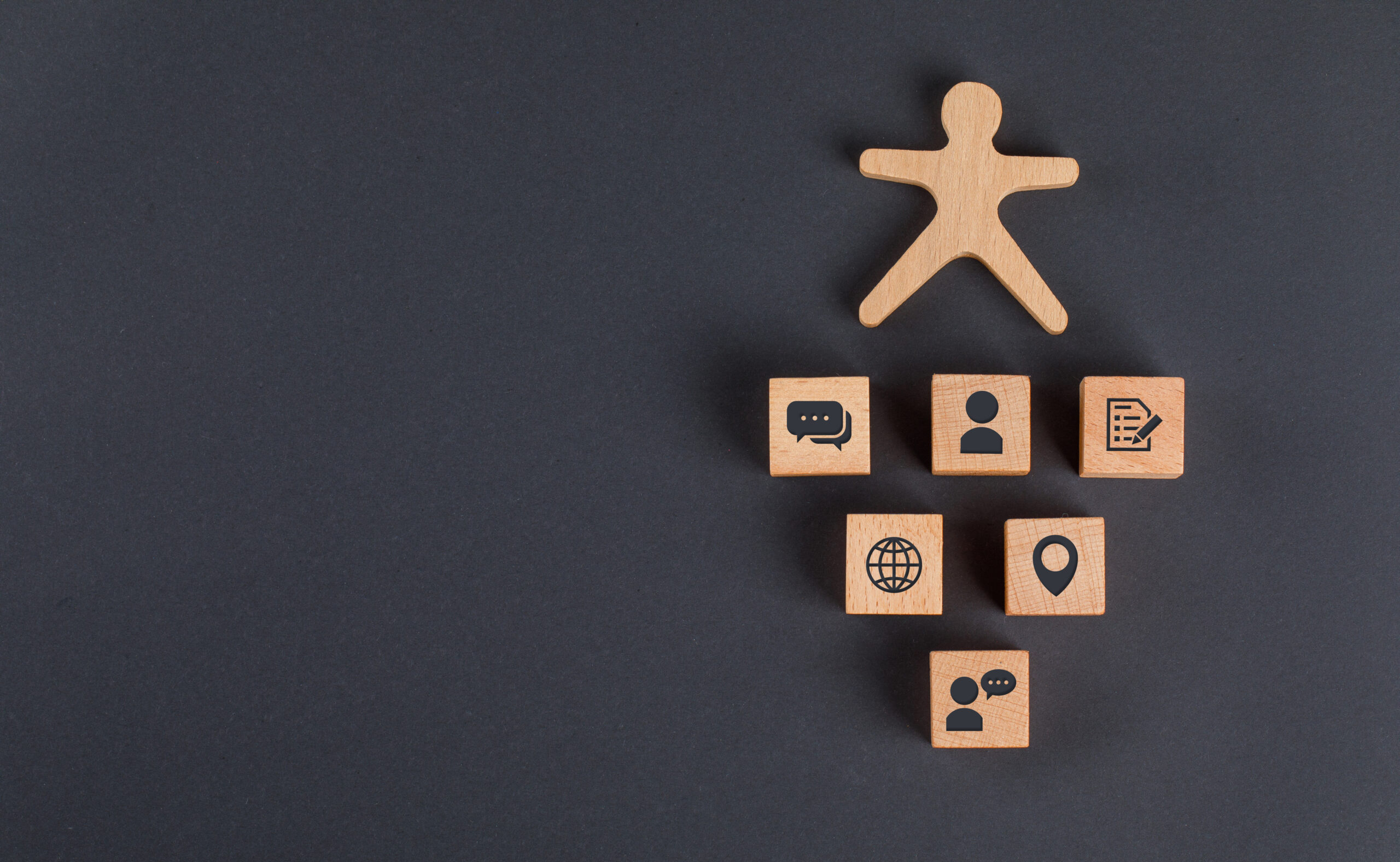 Communication concept with icons on wooden cubes, human figure on dark grey background flat lay.